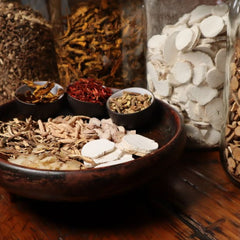 A collection of assorted traditional Chinese herbs and spices in jars and bowls.