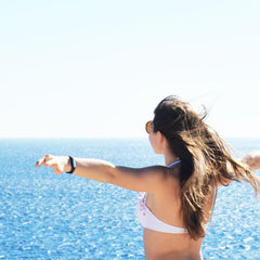 A woman in a bikini enjoying a sunny day by the sea with open arms in Sharm El Sheikh, Egypt.